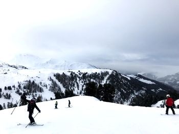 People on snowcapped mountain against sky