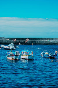 Boats moored in sea against blue sky