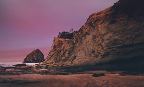 Rock formations by sea against sky during sunset
