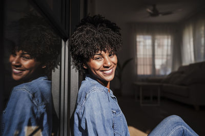 Happy young woman enjoying sunlight in living room at home