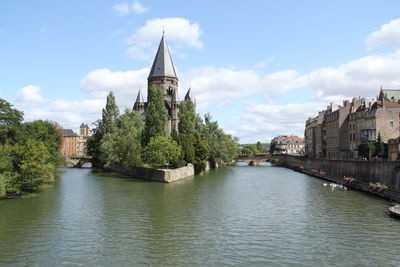 Church by river in city against sky