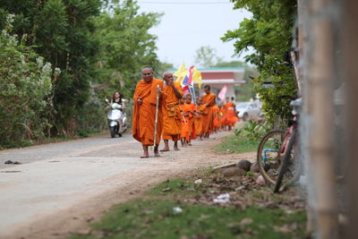 Group of people walking on dirt road amidst trees