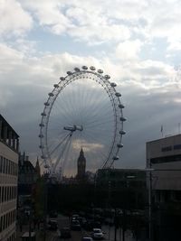 Low angle view of ferris wheel against cloudy sky