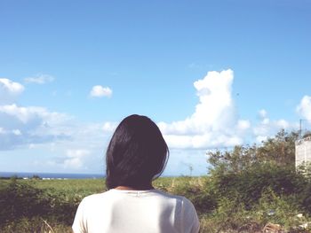 Rear view of woman standing against cloudy sky