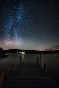 Pier over lake against sky at night