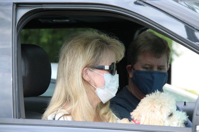 Portrait of young couple in car wearing masks