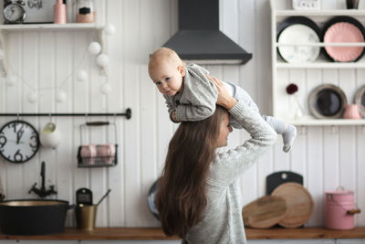 Side view of mother and woman standing in kitchen