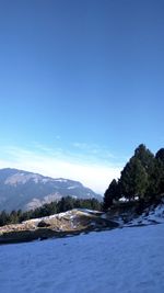 Scenic view of river by mountains against clear blue sky