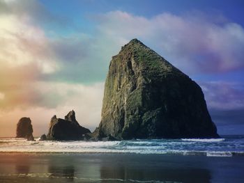 Rock formation on beach against sky