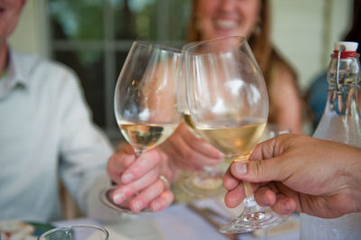 Close-up of hands toasting wine glasses