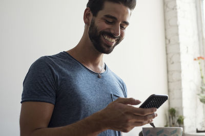 Smiling young man looking on cell phone