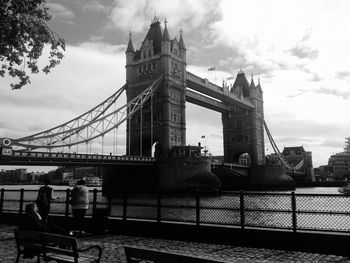 Low angle view of suspension bridge against cloudy sky