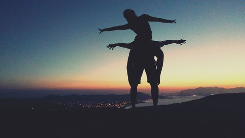 Silhouette man standing on landscape against sky during sunset