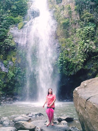 Woman standing on rock against waterfall