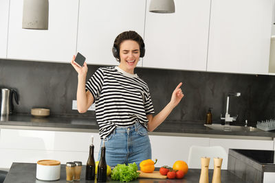 Portrait of young woman preparing food in kitchen