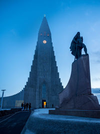 Low angle view of statue and hallgrimskirkja against blue sky