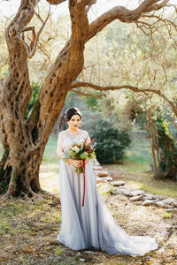 Woman standing by tree trunk