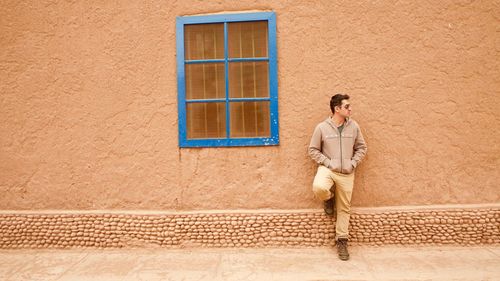 Portrait of man leaning against wall in building