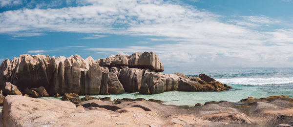 Rock formation on beach against sky