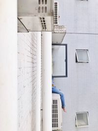 Low section of man sitting against wall