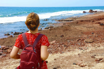 Rear view of woman with backpack standing at beach