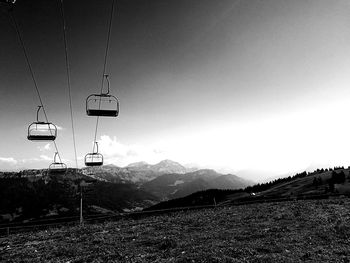 Overhead cable cars over mountains against clear sky