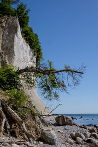 Rock formation by sea against clear sky