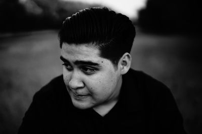 Close-up of teenage boy looking away against blurred background