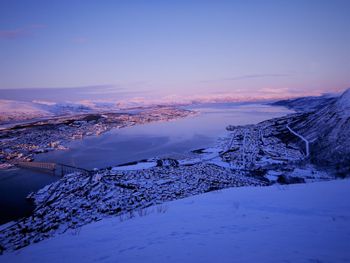 Snow covered landscape against sky during sunset