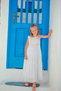 Portrait of young woman standing against wall