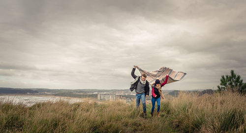 Couple holding blanket on field