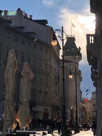 People on street amidst buildings in city at sunset