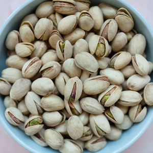 Pistachio in shell in bowl on pink background