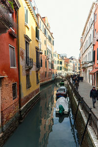 Canal amidst buildings against sky in city