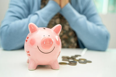Midsection of man with piggy bank on table