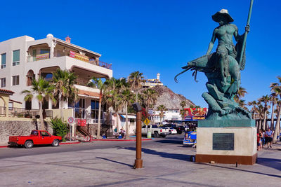 Statue by street against buildings in city against sky