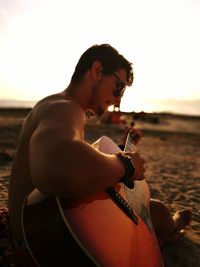 Young man playing guitar at beach