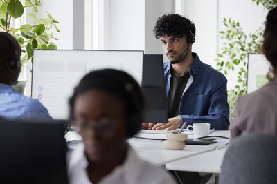 Young man using headset while sitting in office