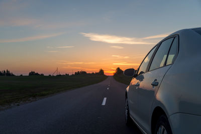 Cars on road against sky during sunset