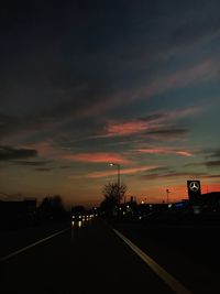 Cars on road against sky at sunset