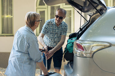 Side view of male friends working in car