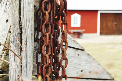 Close-up of rusty metal chain against wooden fence