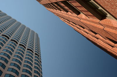 Low angle view of modern buildings against clear blue sky