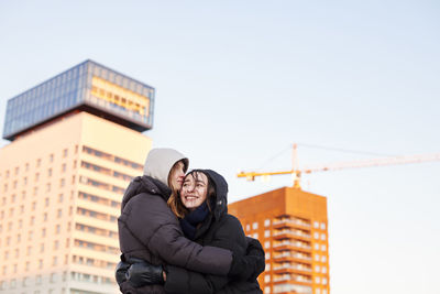 Female couple hugging in modern neighborhood