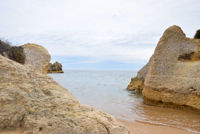 Rock formation on beach against sky