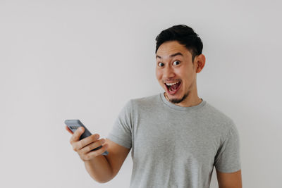 Young man using mobile phone against white background