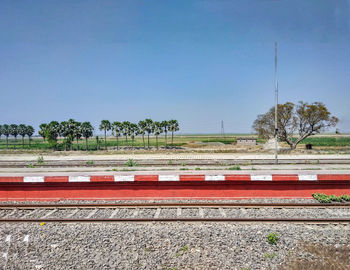 Train by railroad tracks against clear blue sky