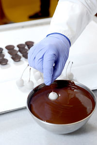 Worker dipping cherries into bowl of chocolate at the chocolate factory

