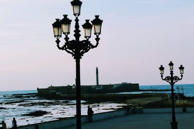 Street light by sea against clear sky