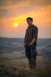 Man standing on field against sky during sunset